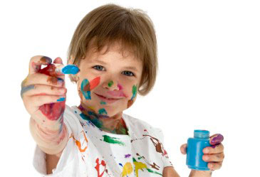 μικρό παιδί χρωματίζει ενώ εχει μπογιές στο πρόσωπο και τα χέρια του